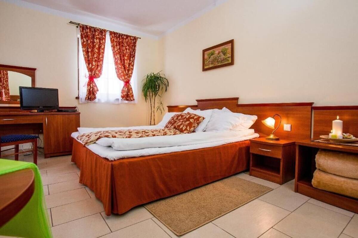 A hotel room with a bed, desk, chair, and a plant.