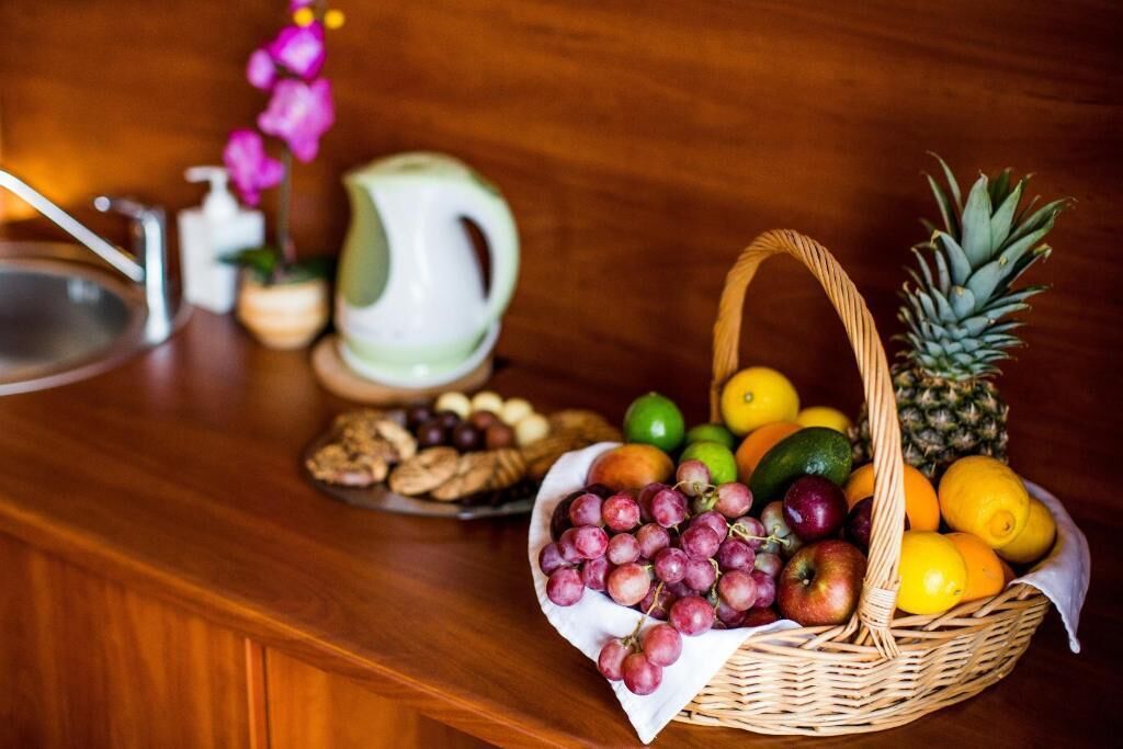 Un comptoir de cuisine avec un panier de fruits, une bouilloire et une assiette de biscuits.