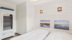 A bedroom with two beds, a wardrobe, wall-mounted artwork, and a ceiling light fixture. - Accommodation for 6, garden, near salt marshes (Ars-en-Ré)