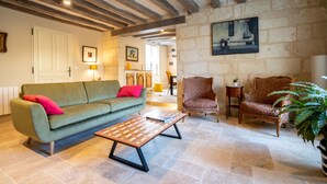 Un salon chaleureux avec un canapé, des fauteuils, une table basse et un tableau accroché au mur.