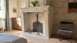 Une pièce avec une cheminée, un lit, une chaise et une commode.