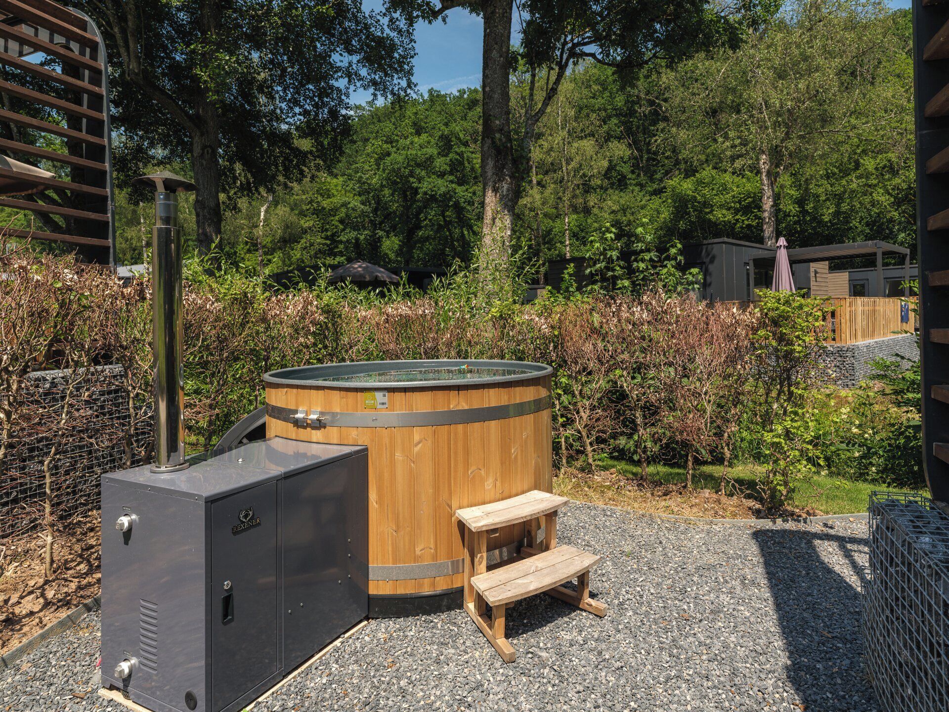 Un bain à remous avec une structure extérieure en bois, un réchauffeur en métal et un banc en bois.