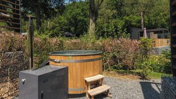 Un bain à remous avec une structure extérieure en bois, un réchauffeur en métal et un banc en bois.