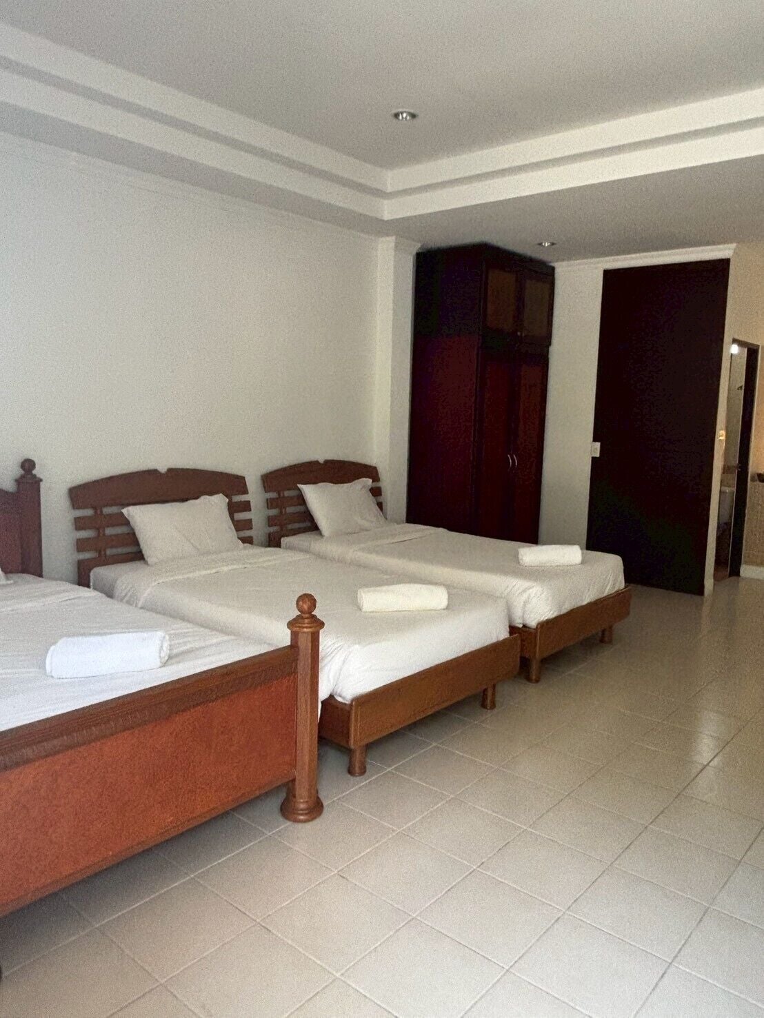 Une chambre d’hôtel avec deux lits, une armoire et une porte donnant sur une autre pièce.