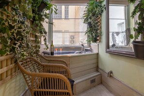 A cozy corner with wicker chairs, a small bar area with a bottle and glasses, and a view of the street through a window. - Marasli 29 1bdr·Serenity Escape with Jacuzzi (Athens)