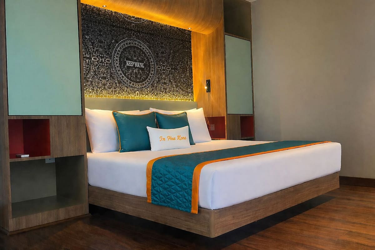 Een moderne hotelkamer met een bed, een hoofdeinde met een decoratief paneel en inbouwplanken.