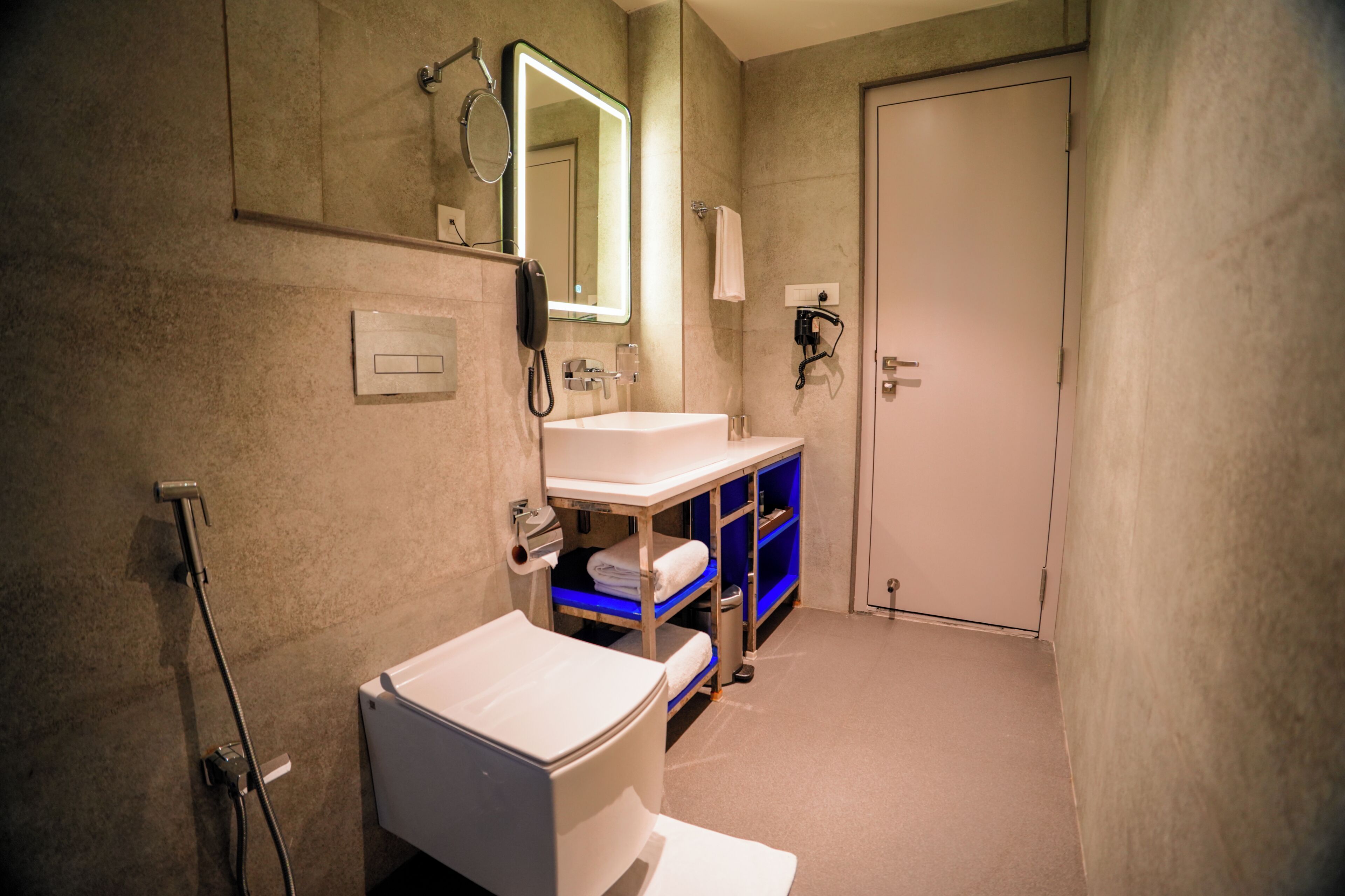 A bathroom with a white sink, a mirror, a towel rack, and a door.