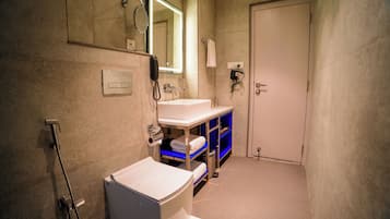 A bathroom with a white sink, a mirror, a towel rack, and a door.