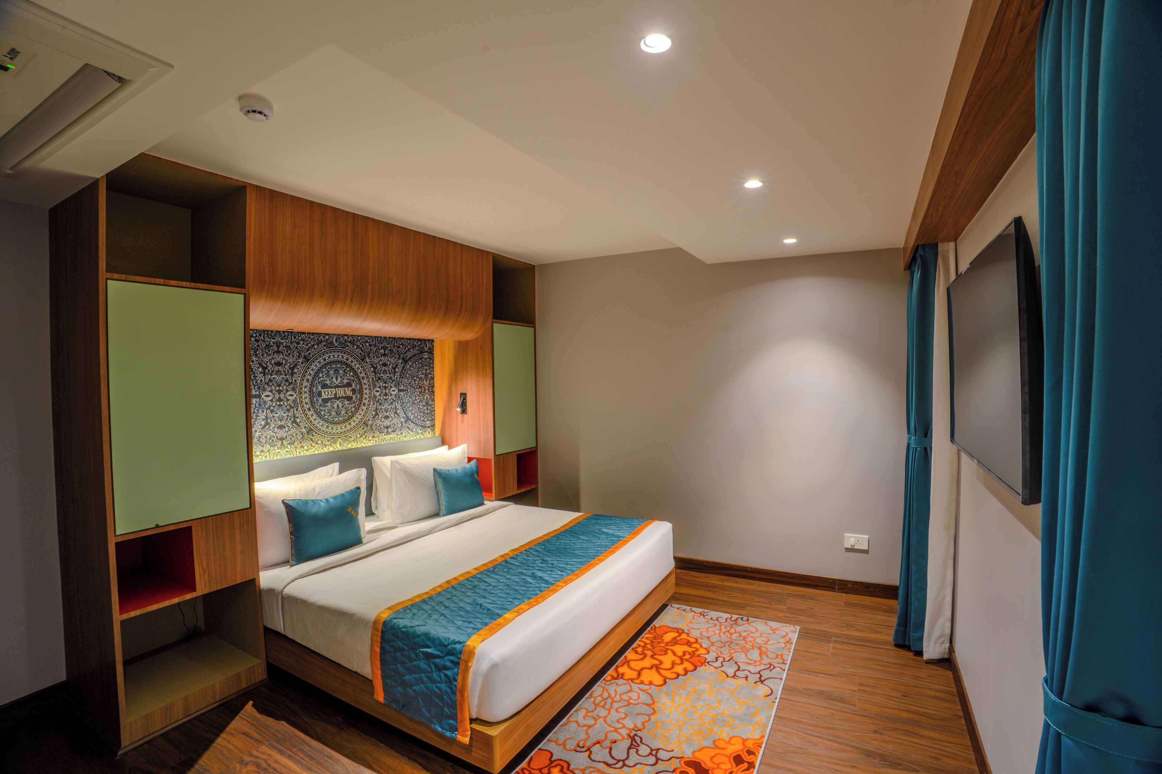 Una habitación de hotel moderna con un marco de cama de madera, una colcha grande y un tapiz decorativo.