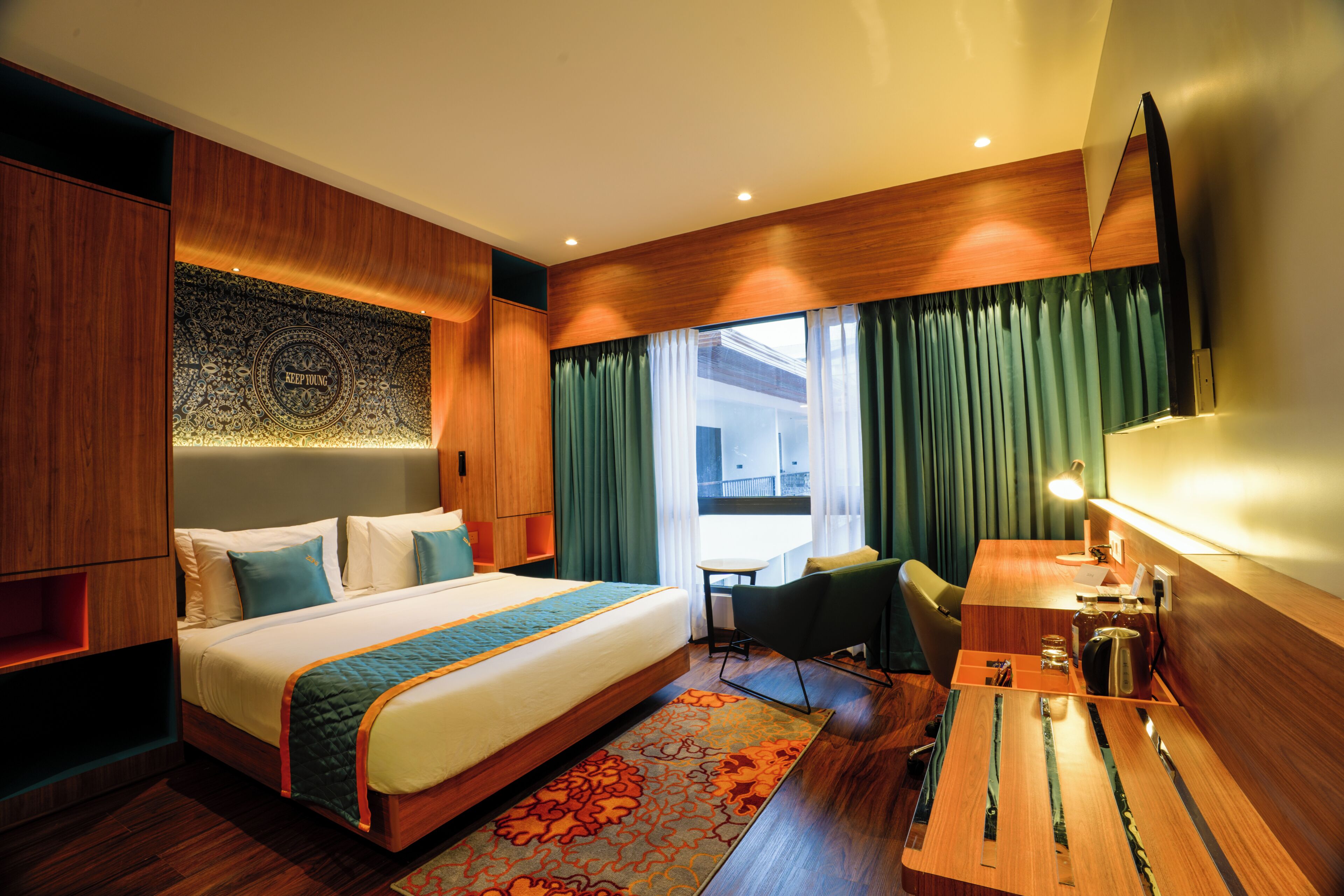 A hotel room with a large bed, a desk, a chair, a desk lamp, and a view of the outside.