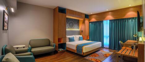 A hotel room with a bed, a sofa, a desk, and a chair.