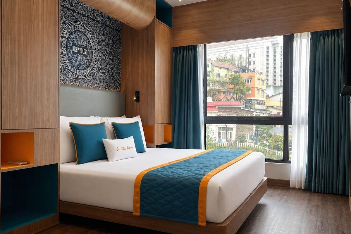 Een hotelkamer met een groot bed, uitzicht op gebouwen en een behang met patroon.