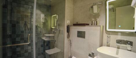A modern bathroom with a glass shower enclosure, a white sink, and a large mirror.
