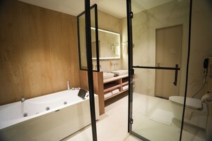A modern bathroom with a bathtub, a toilet, and a shower area.