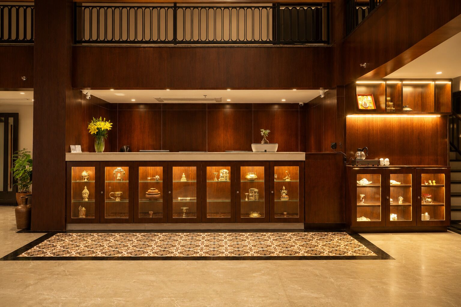 A reception desk with glass display cabinets, a patterned rug, and a staircase in the background.