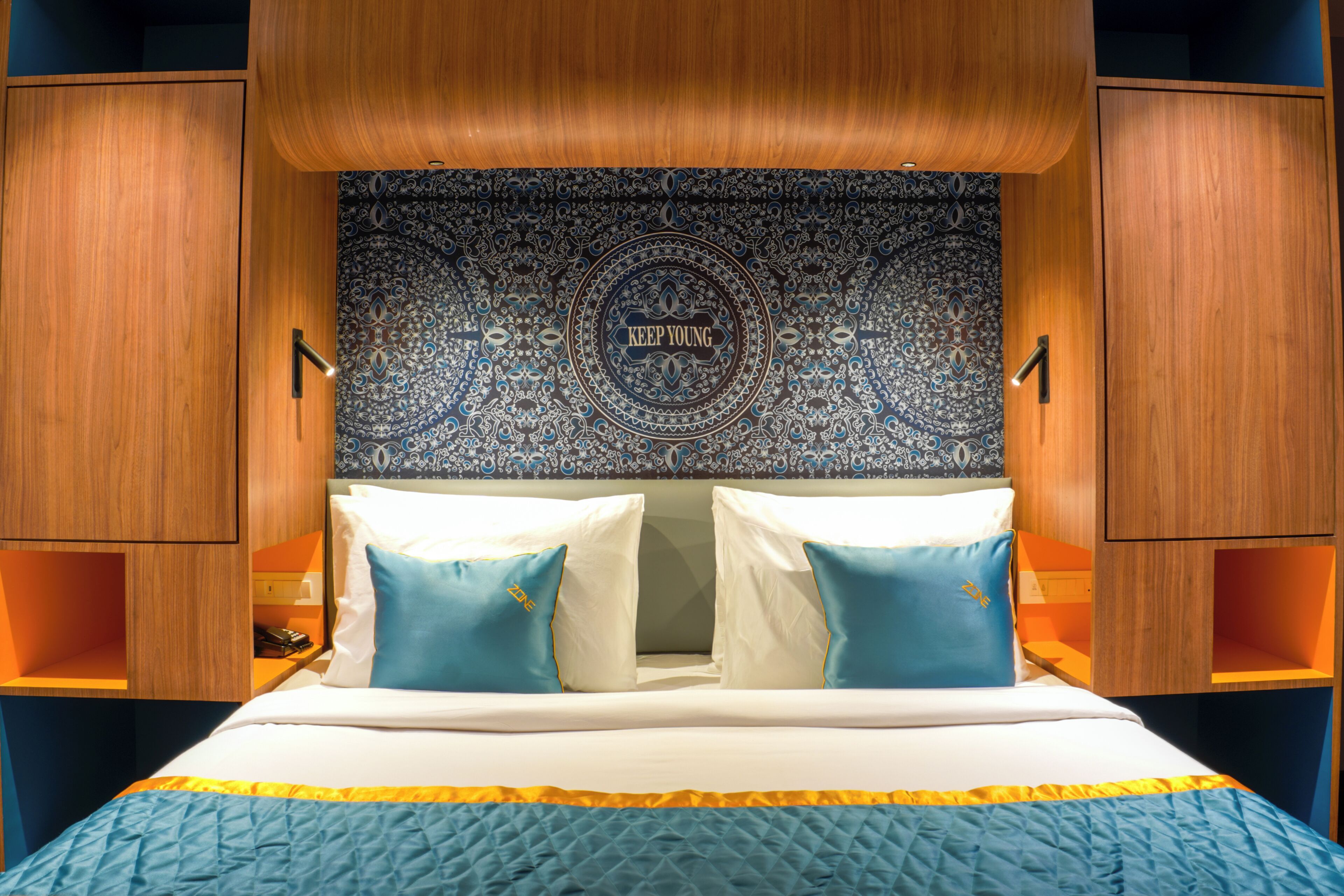 A hotel room with a bed, two pillows, a tapestry, and wooden paneling.