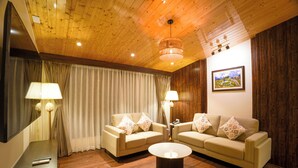 A room with wooden flooring, two sofas with patterned cushions, a round coffee table, a large mirror, and a painting on the wall. - Zone by The Park Darjeeling (Darjeeling)
