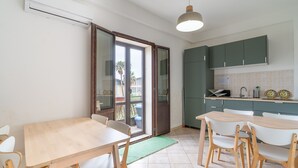 Una cocina con comedor, una puerta corrediza de vidrio al exterior y un mueble verde.