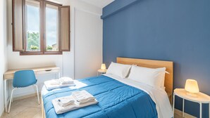 Una habitación con cama, escritorio, silla y ventana.