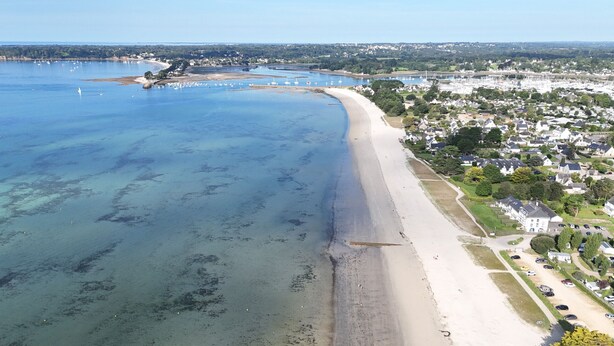 An aerial view of a coastal area with a sandy beach, a marina with boats, and residential buildings. - House for 6 adults and 3 children – 900m beach (La Forêt-Fouesnant)