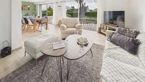 A spacious living area with a sofa, a coffee table, and a TV. There is a dining area with chairs and a table. - House for 6 adults and 3 children – 900m beach (La Forêt-Fouesnant)
