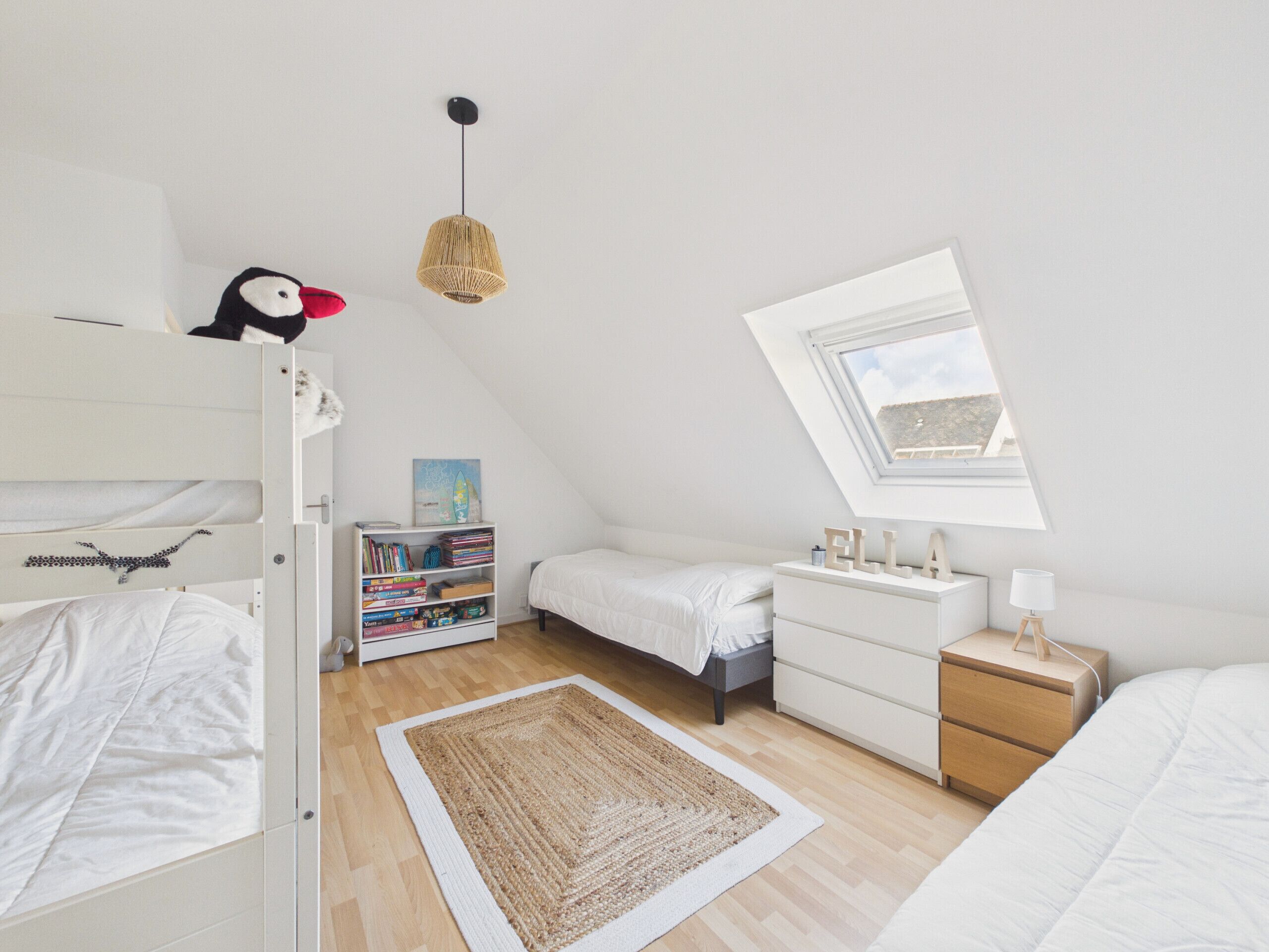 Een slaapkamer met stapelbedden, een boekenplank, een bureau, een lamp en een raam.