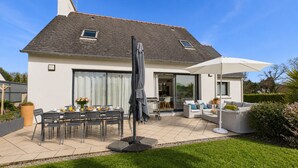 A modern house with a patio, outdoor furniture, and a garden. - House for 6 adults and 3 children – 900m beach (La Forêt-Fouesnant)