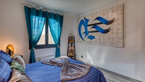 Een slaapkamer met een bed, teal gordijnen, een aan de muur bevestigd kunstwerk en een ladder.