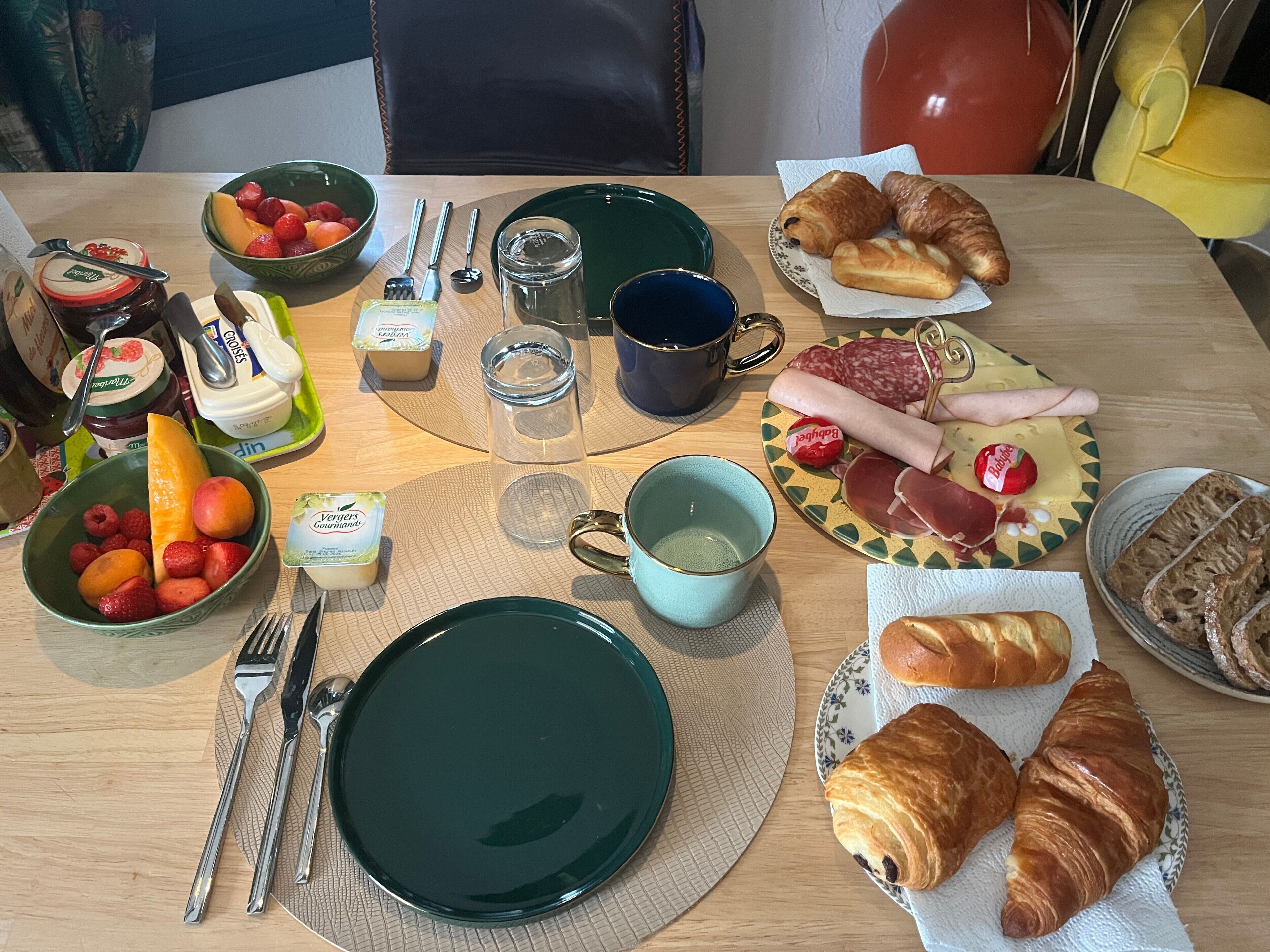 A breakfast setting with various food items, utensils, and a cup on a table.