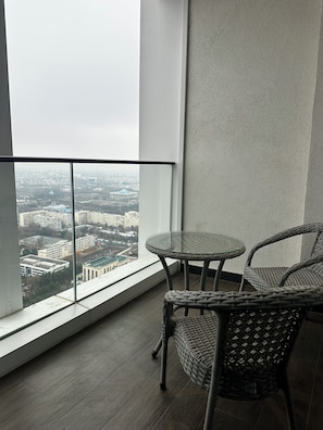 A balcony with a glass table and wicker chairs, overlooking a cityscape. - 35Floor Luxury Apartment | Tashkent’s Tallest Tower |The heart of the city! (Тоshkent)