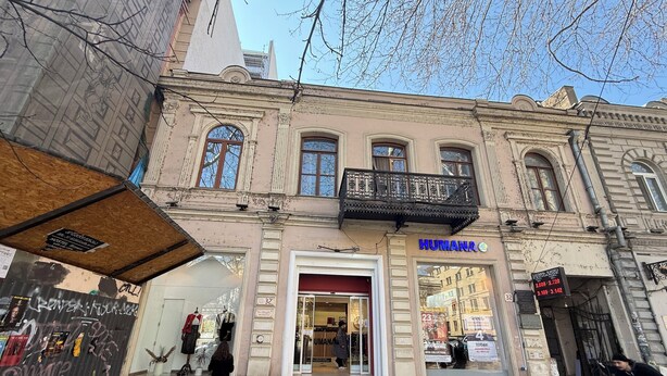 Ein Gebäude mit einer Ladenfront mit der Aufschrift 'HUMANA' und einem Balkon.