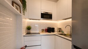 Een moderne keuken met witte kasten, een roestvrijstalen oven en een marmeren aanrecht.