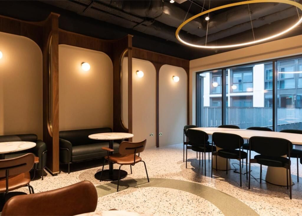 A modern conference room with round tables, black chairs, a black sofa, and a large window.