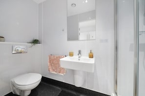 Un baño con inodoro, lavamanos, espejo y ducha.