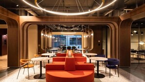 Een modern interieur met ronde tafels, oranje zitplaatsen en een bijzondere ronde lamp.