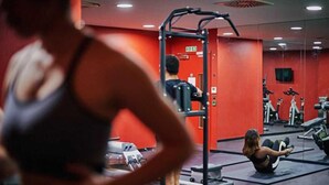 Een sportschool met trainingsapparatuur en een persoon die een apparaat gebruikt.
