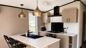 A modern kitchen with a central island, black and white cabinetry, and pendant lighting. - 4-Person Prins Chalet Hoogersmilde (Hoogersmilde)