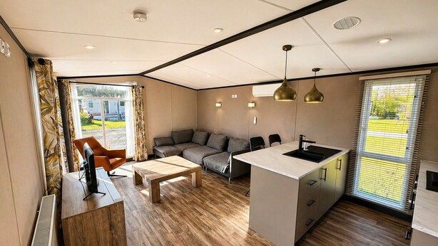 A modern interior with a sofa, coffee table, and kitchen area. - 4-Person Prins Chalet Hoogersmilde (Hoogersmilde)