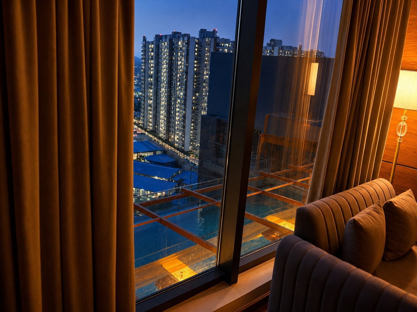 Una habitación con un ventanal grande que da a una vista panorámica de la ciudad al atardecer.