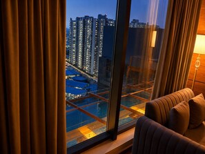 A room with a large window overlooking a cityscape at dusk. - The Murti Hotel and Banquet (Greater Noida)