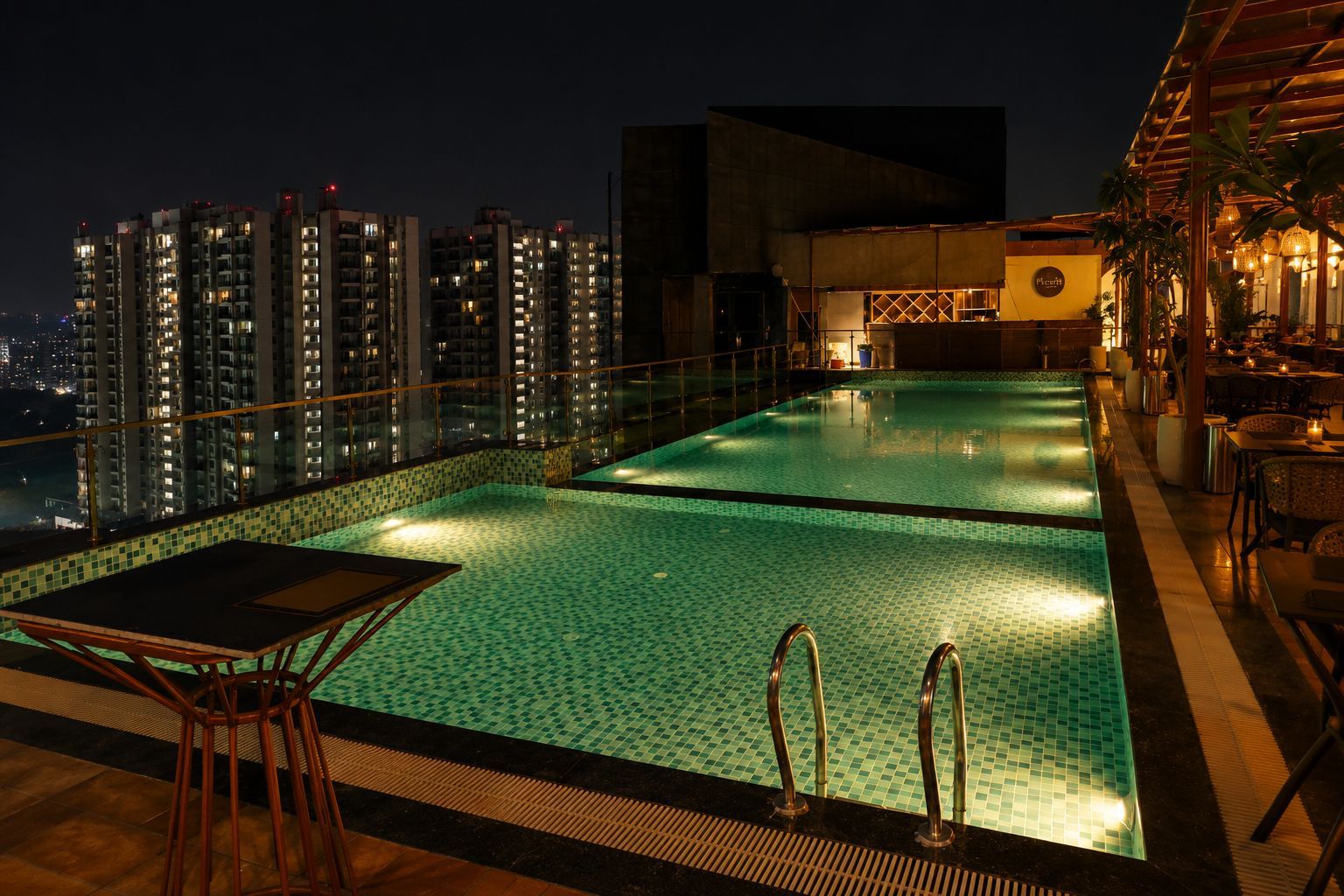 Una piscina en la azotea con vistas a la ciudad, un área de bar y un comedor.