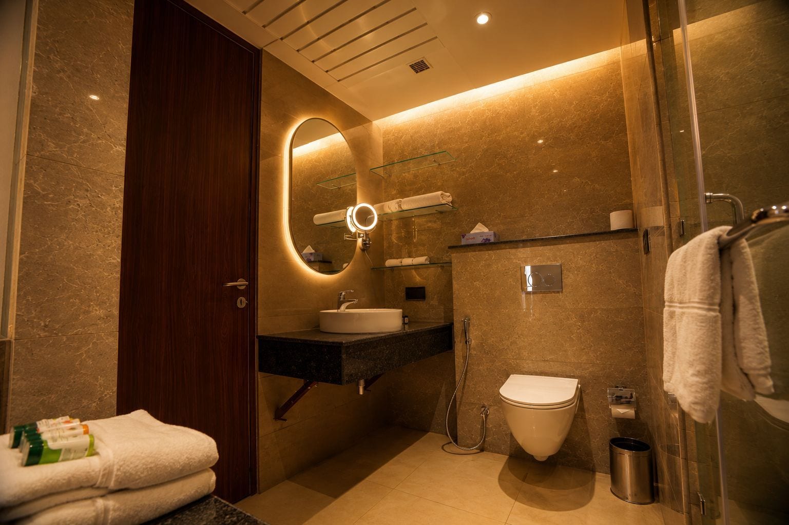 A modern bathroom with a vanity, mirror, toilet, and shower.
