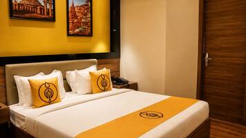 A hotel room with a bed, two pillows, a bedside table with a phone, and a door.