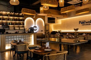 Un interior de restaurante con zona de bar, disposición de mesas y lámparas decorativas.