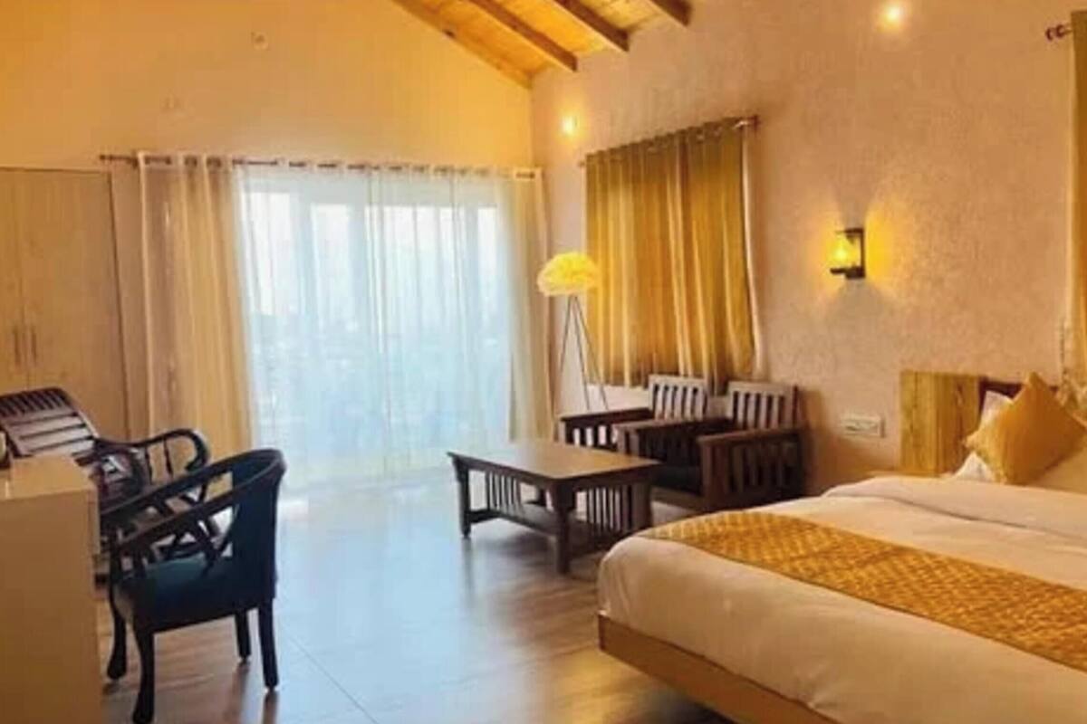 A hotel room with a bed, a desk, a chair, and a lamp.