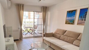 A living room with a sofa, a glass coffee table, a potted plant, and a balcony with outdoor furniture. - Sweet Escape apartment on the beachfront (Orpesa)