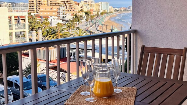 A balcony with a table, a glass pitcher of orange juice, and a view of the beach and buildings. - Sweet Escape apartment on the beachfront (Orpesa)