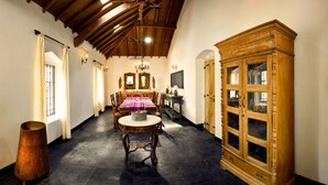 Una habitación con techo alto, una araña, un aparador de madera, una mesa de comedor con sillas y un ventanal grande.