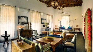 Una habitación tradicional con una mesa de comedor de madera, sillas, un sofá y una cama con almohadas azules.