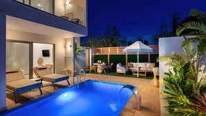 A modern outdoor pool area with lounge chairs, a small table, and a covered seating area.